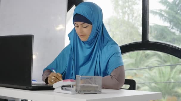 Красивая сауди бизнес-женщина в хиджабе работает в офисе с помощью ноутбука, копировать пространство — стоковое видео
