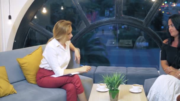 The concept of psychological health in a big city. A woman psychologist consults a woman and her teenage daughter in an office with a large beautiful window from which the lights of the modern city — Stock Video