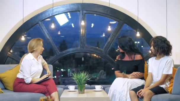 큰 도시 개념의 가족 상담 및 사회화 문제. 한 여성 심리학자가 사무실에서 한 여성과 십대 아들을 상담하고 있는 커다란 아름다운 창문이 있습니다. — 비디오