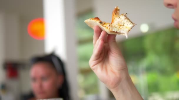 Close-up. vrouw die pizza eet terwijl je in een restaurant met vrienden zit — Stockvideo