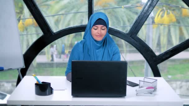 Красивая сауди бизнес-женщина в хиджабе работает в офисе с помощью ноутбука, копировать пространство — стоковое видео