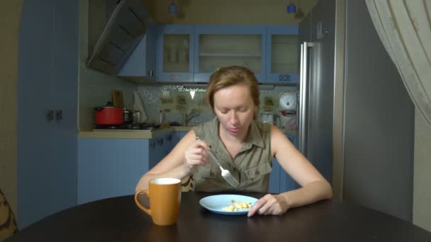 Диетическая концепция, безвкусная еда. Разочарованная и раздраженная женщина ест еду с тарелки и разочарована — стоковое видео