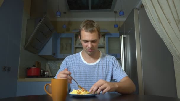 Dieet concept, smakeloos eten. Gefrustreerd en geïrriteerd man eten eten van een bord en teleurgesteld — Stockvideo