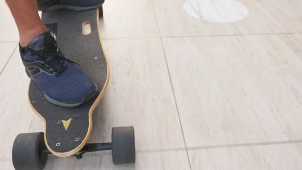 Vista dall'alto. uomo in scarpe da ginnastica nere cavalca su uno skateboard elettrico sull'asfalto . — Video Stock