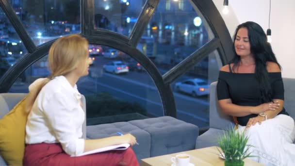 Dos mujeres hablando en una oficina espacio libre sentado en sofás, multinacionales de negocios mujeres tomando café y charlando — Vídeo de stock