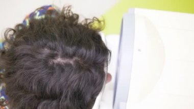 Oftalmoloji kavramı, optometri. Göz muayenesi için tıbbi oftalmik cihaz. Genç bir çocuk bir doktor randevusunda görme yetisini kontrol eder, ekipman.