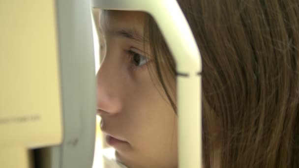 O conceito de oftalmologia, optometria. Dispositivo oftálmico médico para exame ocular. menina adolescente verifica a visão em uma consulta médica, no equipamento . — Vídeo de Stock