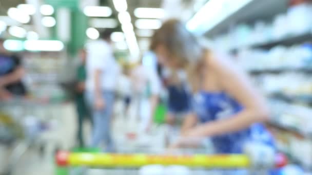 Mensen in de supermarkt, onscherpe achtergrond. kopers kiezen producten in de supermarkt. — Stockvideo