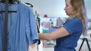 genç kadın bir butik yeni giysiler bulma. Etiketleri okur ve seçer.