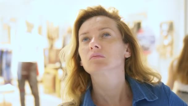 Vrouw kijkt naar etalages in een grote supermarkt. gezicht close-up — Stockvideo