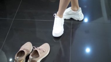 Bir ayakkabı mağazasında beyaz spor ayakkabı çalışıyor genç kadın