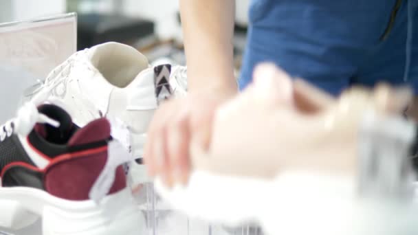 Молодая женщина примеряет белые кроссовки в обувном магазине — стоковое видео