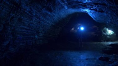 bir fener ile kadın turist yapay aydınlatma ile bir mağara içinde geçer.