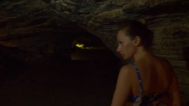 Turista mulher com uma lanterna passa dentro de uma caverna com iluminação artificial . — Vídeo de Stock