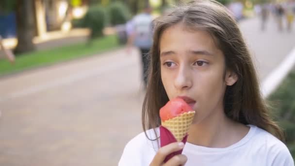 Menina adolescente comendo sorvete ao ar livre. O conceito de infância, estilo de vida, comida, verão . — Vídeo de Stock