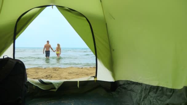 Concetto campeggio in riva al mare. vista dalla tenda, una coppia uomo e donna coccole, in piedi nel mare — Video Stock