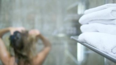 Kadın duşta başını yıkıyor. Açık camdan görünüm.