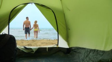 Deniz de kamp konsepti. çadırdan görünümü, bir çift adam ve kadın sarılma,