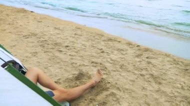 Deniz de kamp konsepti. bir erkek ve kadının bacakları denizin arka planına karşı kum üzerinde bir çadır dan görülebilir.