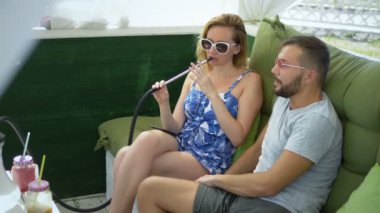 çift erkek ve kadın açık güneşli bir günde çardak içinde nargile duman ve konuşmak