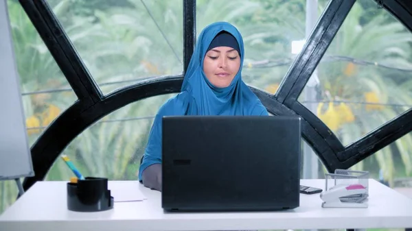 Hermosa mujer de negocios saudí en hijab trabajando en la oficina utilizando el ordenador portátil, espacio de copia — Foto de Stock