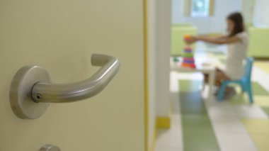 Bir kız bir çocuk kliniğinin lobisinde oturur, bir doktorla buluşmayı bekler, çocuk piramidini sıralar. Tıbbi muayene kavramı, sağlık takibi, önleyici muayene