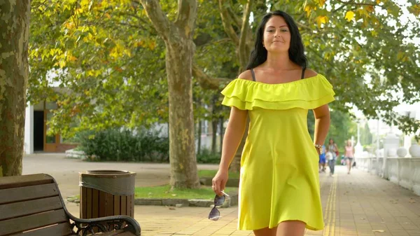 Schöne junge brünette Frau zu Fuß in einem Park an einem heißen Sommertag. — Stockfoto