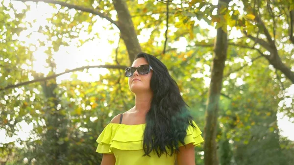 Schöne junge brünette Frau zu Fuß in einem Park an einem heißen Sommertag. — Stockfoto