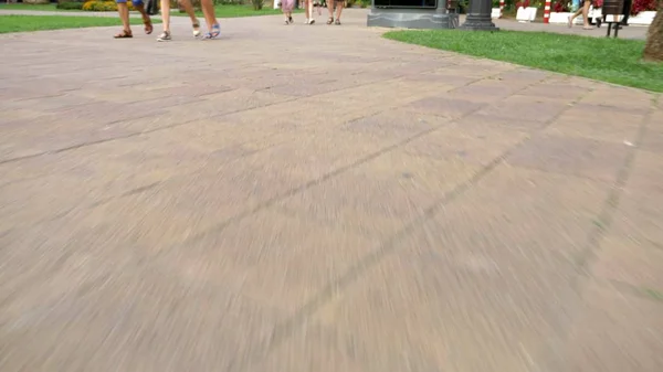 Mouvement le long d'une passerelle piétonne pavée. Des gens méconnaissables marchent sur la route avec leurs pieds. Un groupe de touristes, des piétons traversant la rue ensemble. Jambes mâles et femelles — Photo