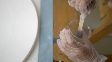 yakın çekim, tek kullanımlık bir fincan boya karıştırma. sanatçılar işyeri. tuval üzerine akrilik boyalar ile çalışmak için iş akışının hazırlanması. sanat sıvısı