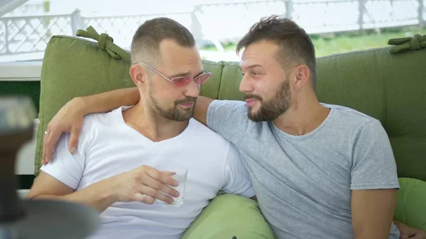 Pareja gay fuma un hookah, sentado en el gazebo en la calle en un soleado día de verano . —  Fotos de Stock