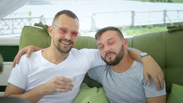 Gay couple smokes a hookah, sitting in the gazebo on the street on a sunny summer day. — Stock Photo, Image