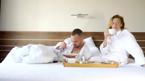 Junges Paar, das morgens zusammen im Bett liegt, frühstückt im Bett — Stockfoto