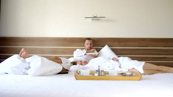 Junges Paar, das morgens zusammen im Bett liegt, frühstückt im Bett — Stockfoto