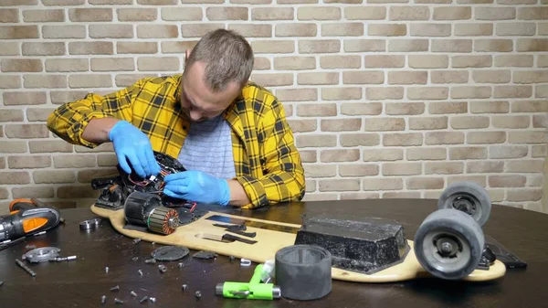 一位男技工正在修理坐在阁楼车间的电动溜冰鞋。总体规划 — 图库照片
