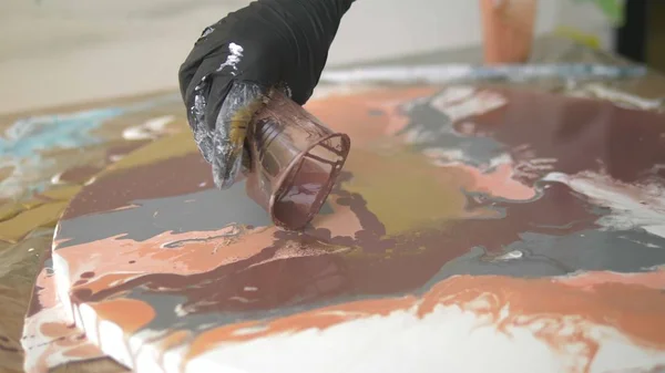 Taller de acrílicos líquidos. Arte fluido. manos femeninas vertiendo pintura acrílica sobre lienzo. Trabajos creativos — Foto de Stock