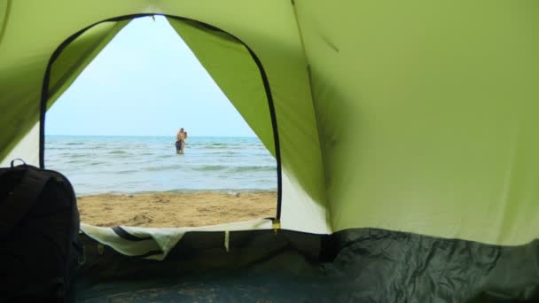 Camping konceptet vid havet. utsikt från tältet, ett par man och kvinna krama, — Stockvideo
