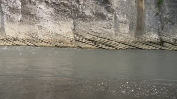 Het heldere en wilde water van een berg rivier die in de kliffen van een kloof klopt. Puur natuur, een klif met groen aan de top, zon en water. — Stockvideo