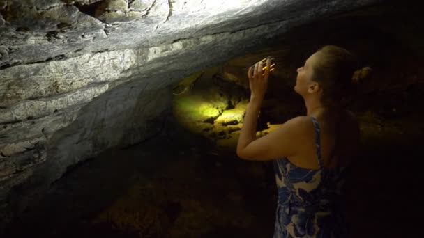 Жінка-турист з ліхтарем проходить всередині печери зі штучним освітленням . — стокове відео