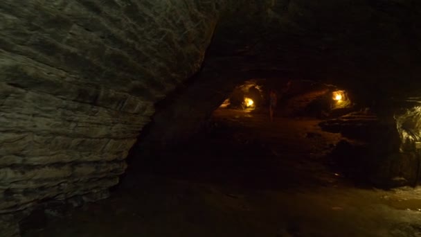 Kobieta turysta z latarni przechodzi wewnątrz jaskini ze sztucznym oświetleniem. — Wideo stockowe