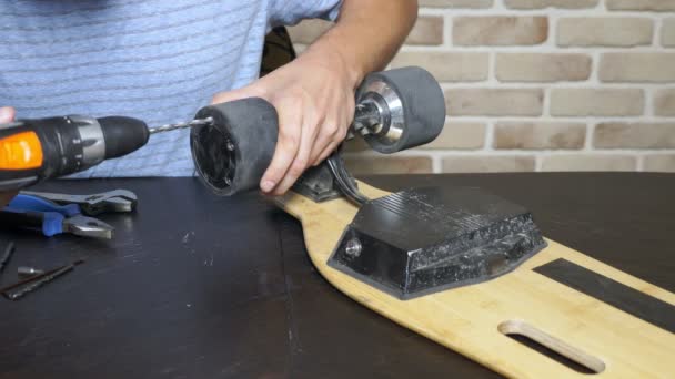 Close-up.Man hands who repair a broken electric skateboard. unscrews the wheels — Stock Video