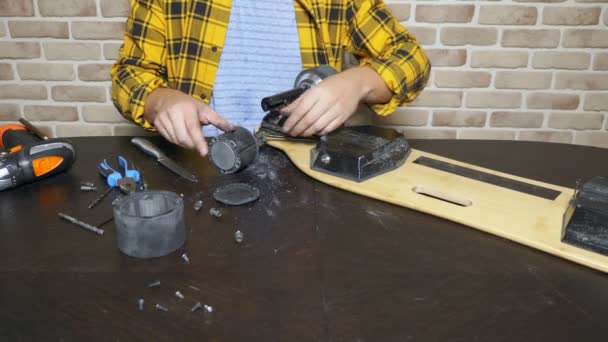 Close-up. Man handen die een gebroken elektrisch skateboard repareren. Schroef de wielen los — Stockvideo