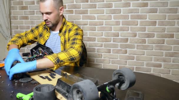 A male mechanic is repairing an electric skate sitting in a workshop in a loft. master plan — Stock Video