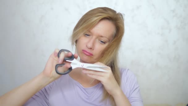 Concept of damaged long hair. blond woman cuts hair ends with scissors. — Stock Video