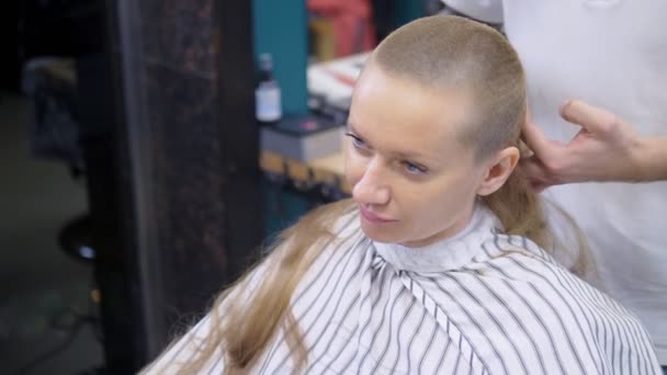 Vrouw scheren haar hoofd baldly. een kapper scheert een Womans lang haar met een haar Clipper. — Stockvideo