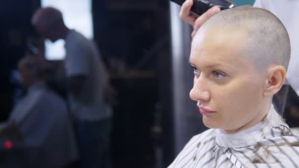 化学療法後の脱毛の概念。美容師は化学療法の後に生き残ったはげの女性の頭の上の髪の残りの部分を剃ります。生存への希望. — ストック動画
