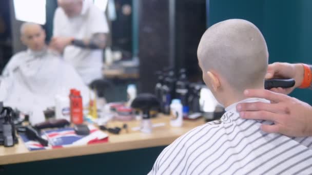 Konzept des Haarausfalls nach Chemotherapie. Der Friseur rasiert einer Frau mit Glatze, die nach einer Chemotherapie überlebt hat, die übrigen Haare auf dem Kopf. Hoffnung auf Überleben. — Stockvideo