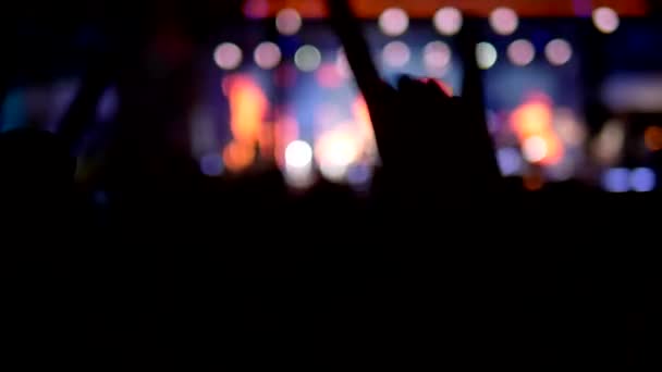 Fundo desfocado, silhuetas de fãs. concerto de rock à noite. as pessoas na multidão levantam as mãos e aplaudem . — Vídeo de Stock