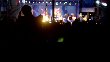 bulanık arka plan, fanlar siluetleri. akşam rock konseri. kalabalıktaki insanlar ellerini kaldırıp alkışlıyorlar..
