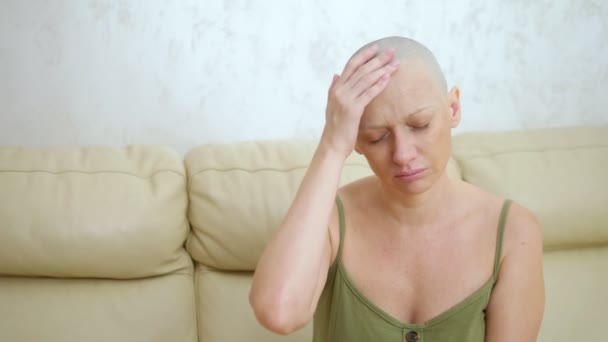 Depresso triste donna calva, paziente oncologico, dopo chemioterapia. seduta sul divano gli tocca la testa — Video Stock